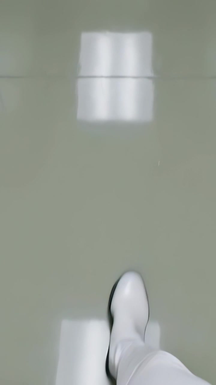 Video verticale: Piede che entra, persona con pantaloni bianchi che cammina su piastrelle lucide, riflessi di luce.
