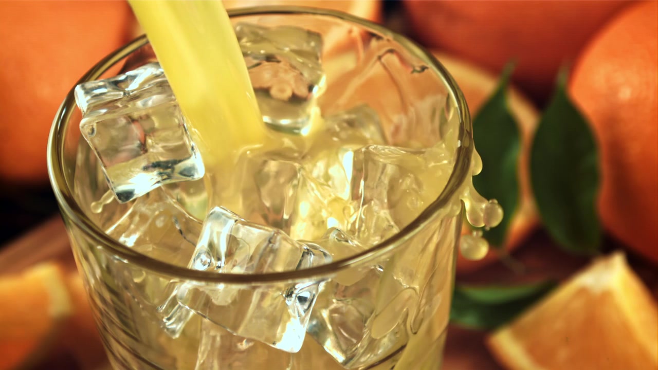 Succo d'arancia rinfrescante versato su ghiaccio in un bicchiere.