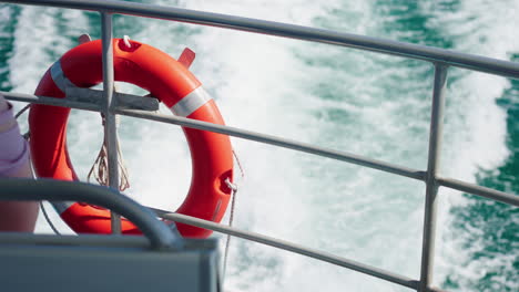 Close-Up-Of-Orange-Life-Preserver-Life-Ring-On-Back-Of-Boat-Overlooking-Ocean,-4K-Slow-Motion