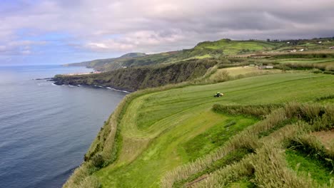 Tractor-Cosechando-Campo-Verde-En-El-Acantilado-De-La-Costa-Del-Mar,-Azores,-Paso-Elevado