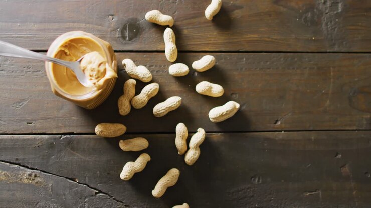Video of close up of peanut butter and peanuts on wooden background
