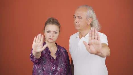 Couple-looking-at-camera-and-making-stop-sign.