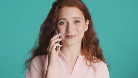 Redheaded-girl-in-front-of-camera-on-turquoise-background.