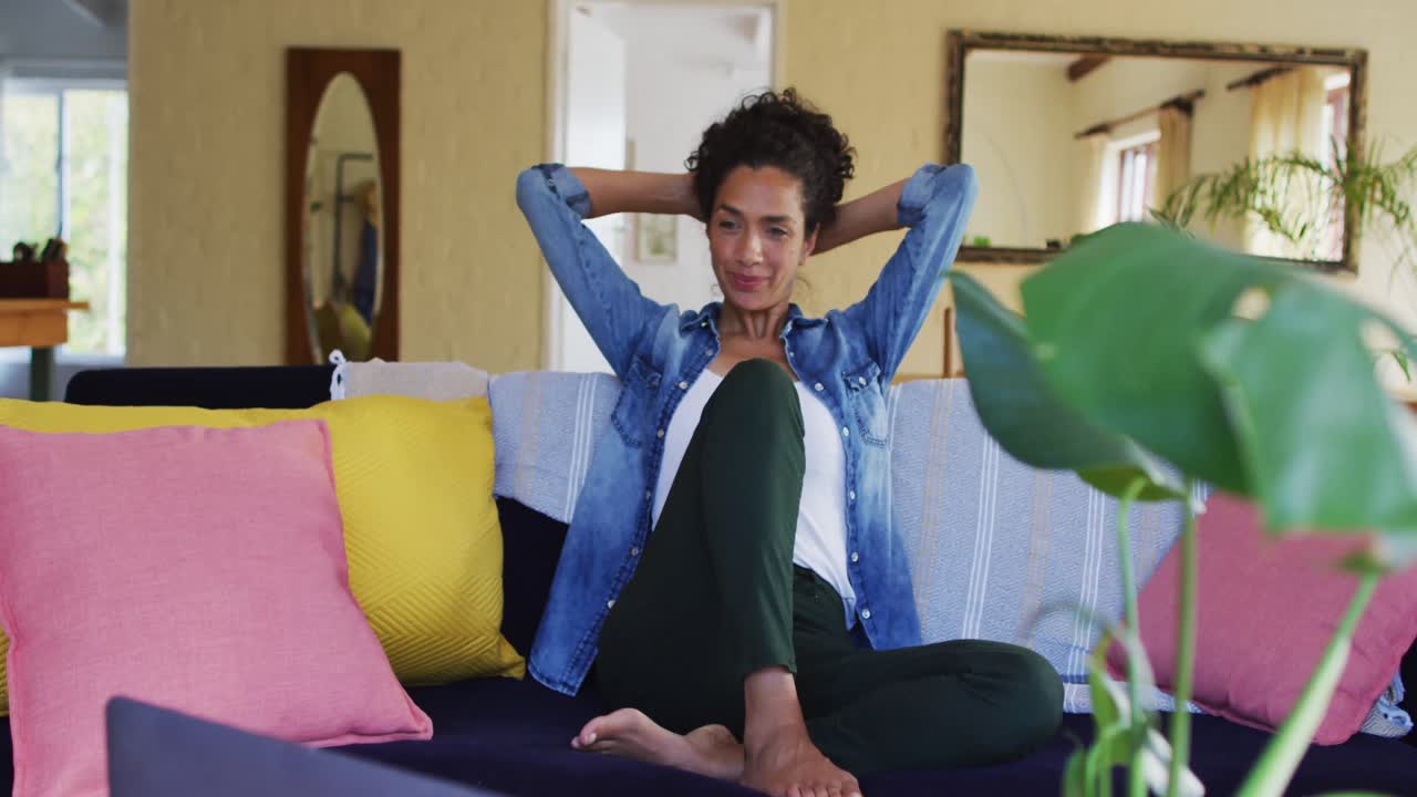 mujer caucásica sonriente sentada en el sofá, relajándose en casa