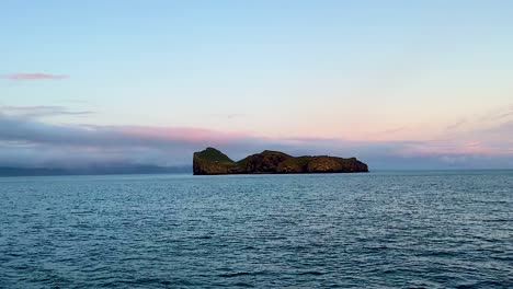 wide view of distant secluded island ellidaey with house and open ocean, vestmannaeyjar, iceland