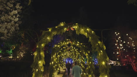 Wide-steadicam-shot-of-walkway-decorated-with-Christmas-lights-and-Arches,-Night