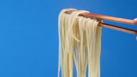 boiled pasta spaghetti with hot steam on the wooden forceps.