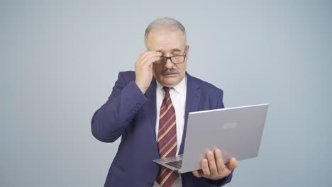 hombre de negocios mirando la computadora portátil con expresión cansada.