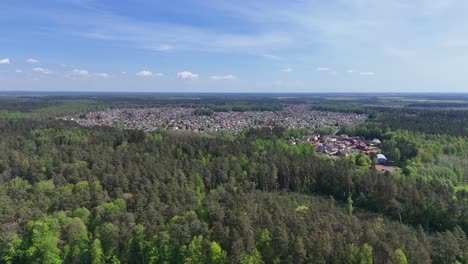 Eine-Kleine-Stadt,-Umgeben-Von-Dichten-Grünen-Wäldern-Und-Einem-Fluss-An-Einem-Sonnigen-Tag,-Luftaufnahme