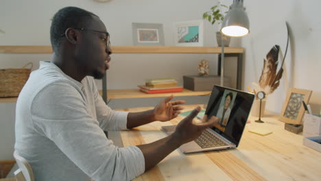 african man chatting on video call on laptop at home