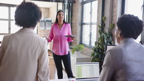 presenting business strategy, woman holding tablet speaking to colleagues in office meeting