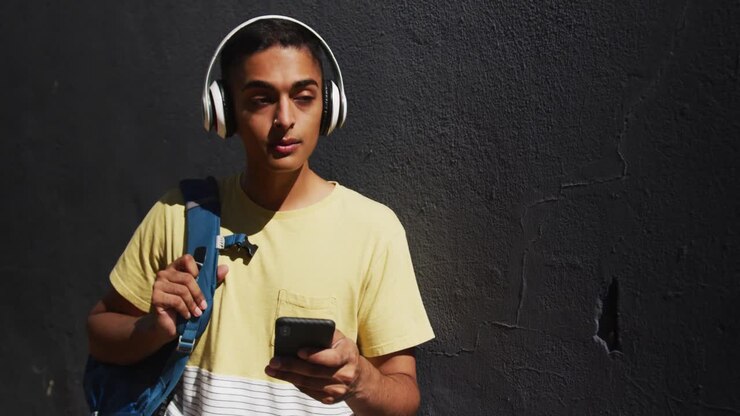 Uomo multietnico con le cuffie che usa lo smartphone per strada.