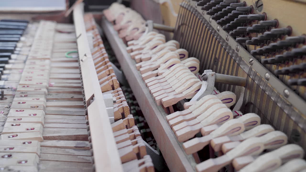 Primo piano di un antico pianoforte rotto suonato con i martelletti che colpiscono le corde