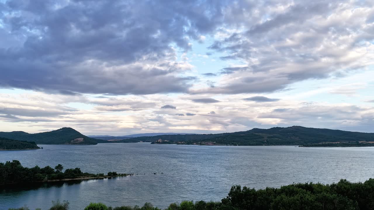 Dramatic clouds moving over a calm lake and hills landscape