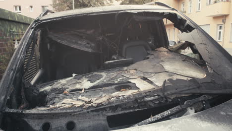 primer plano de un coche quemado abandonado en el patio