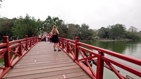 people walking on a red bridge in hanoi