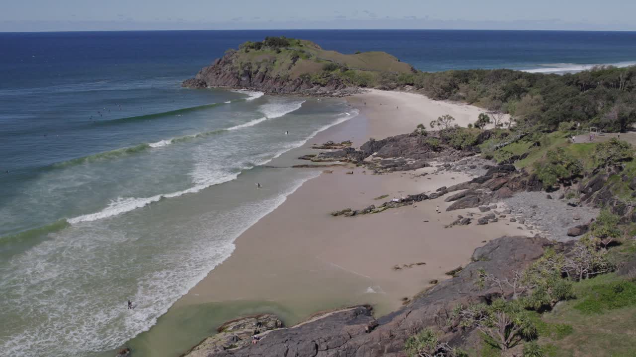 olas del océano salpicando en la orilla arenosa en la playa de cabarita en nsw, australia - retroceso aéreo