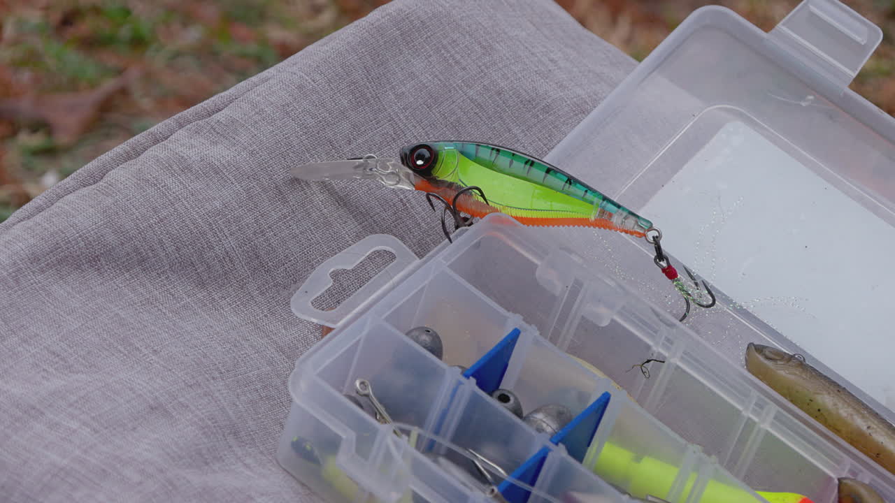 A close-up view of an open tackle box reveals a colorful treble hook prominently displayed, showcasing the essential gear for a successful fishing trip