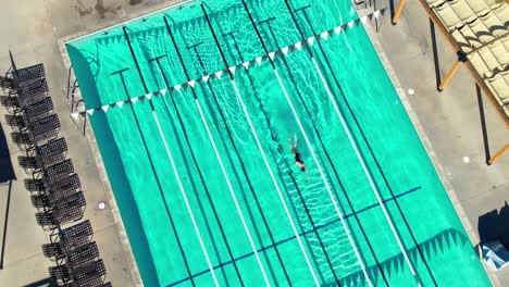 Vista-Aérea-De-Pájaros-De-Una-Mujer-Solitaria-Nadando-En-Una-Piscina-Olímpica-En-Un-Día-Soleado