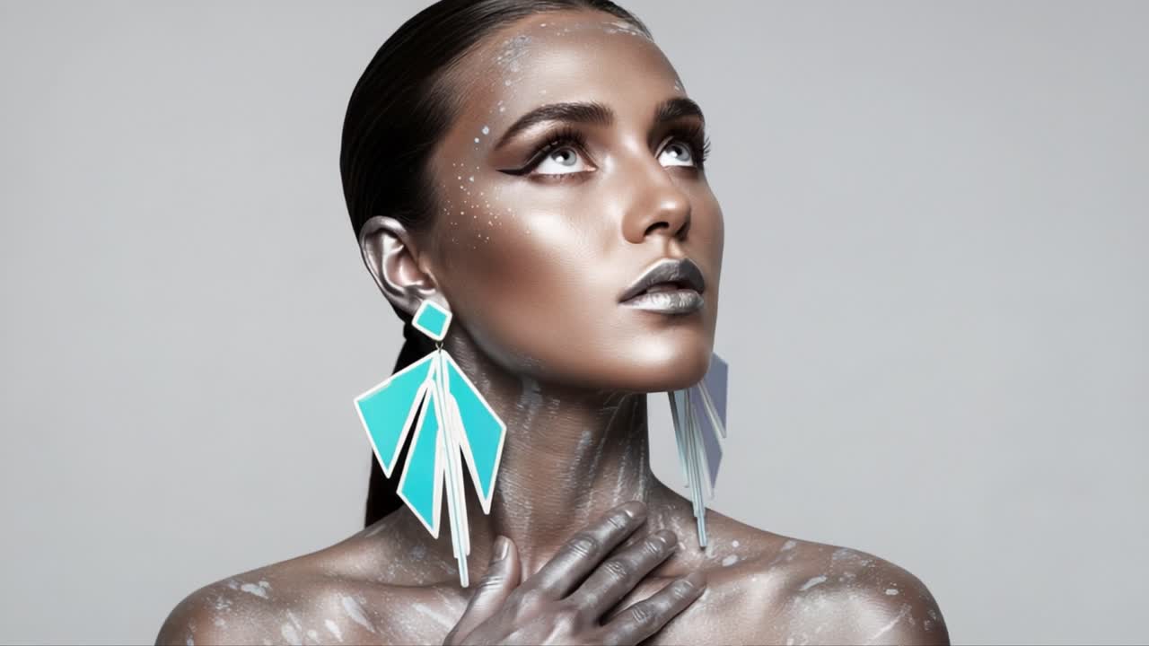 A striking model showcases futuristic beauty with metallic makeup and vibrant geometric earrings against a minimalist gray background, captivating the essence of modern artistry