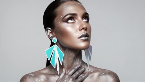 a striking model showcases futuristic beauty with metallic makeup and vibrant geometric earrings against a minimalist gray background, captivating the essence of modern artistry