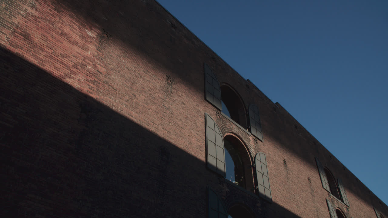 Shadows and a beam of light cast on a brick wall in Brooklyn