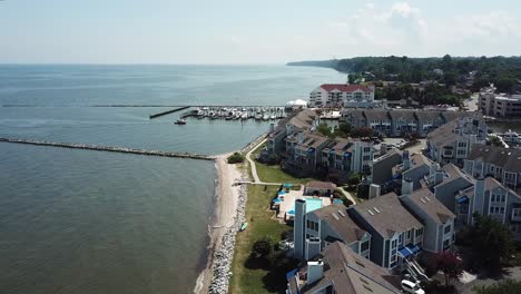 cinematic aerial of chesapeake bay beach properties, jetty and boats in marina on sunny summer day