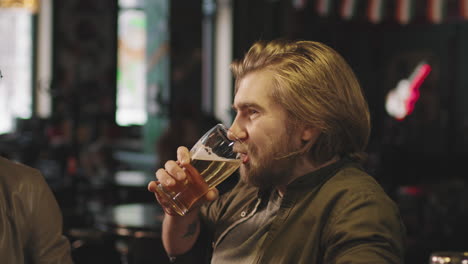 bearded man with beer talking in bar