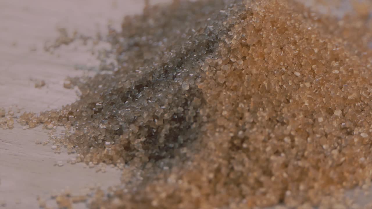 Close Pile of Brown Sugar Granules Rotating on a Wooden Board