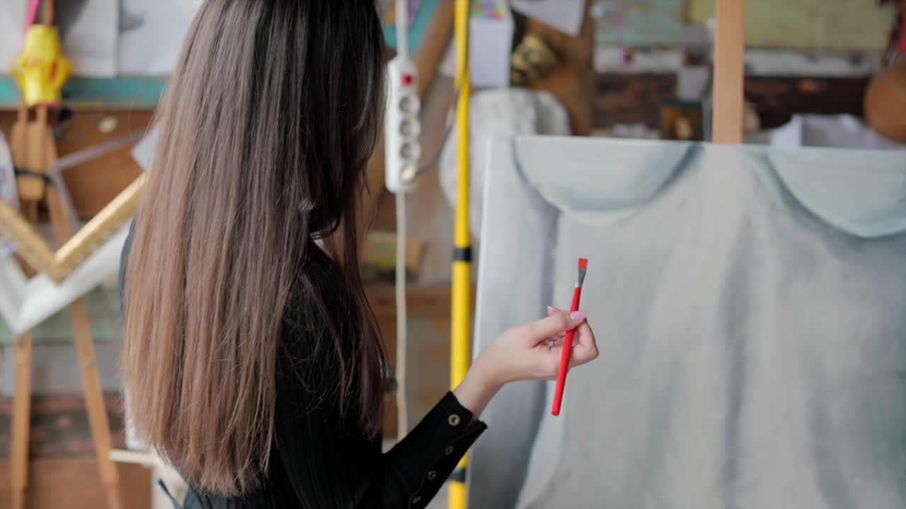 Woman painter wearing black clothes painting woman model at a workshop