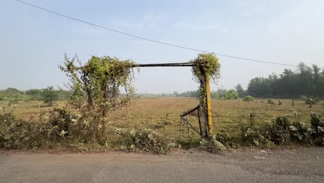 wide angle shot of an empty goal post in small town of a village beside a road in india