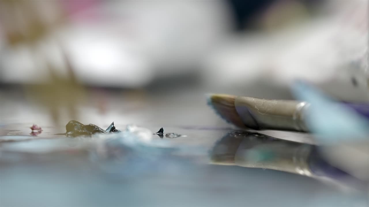 濡れた絵の具パレットの上に置かれた汚れた絵筆の超クローズアップ。