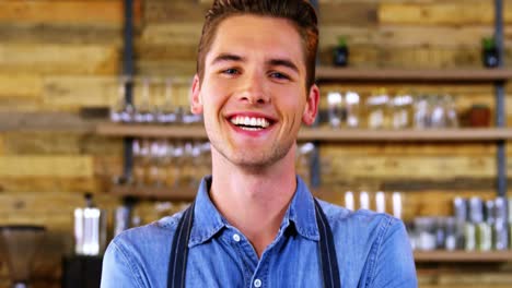 retrato de un camarero sonriente de pie en el mostrador