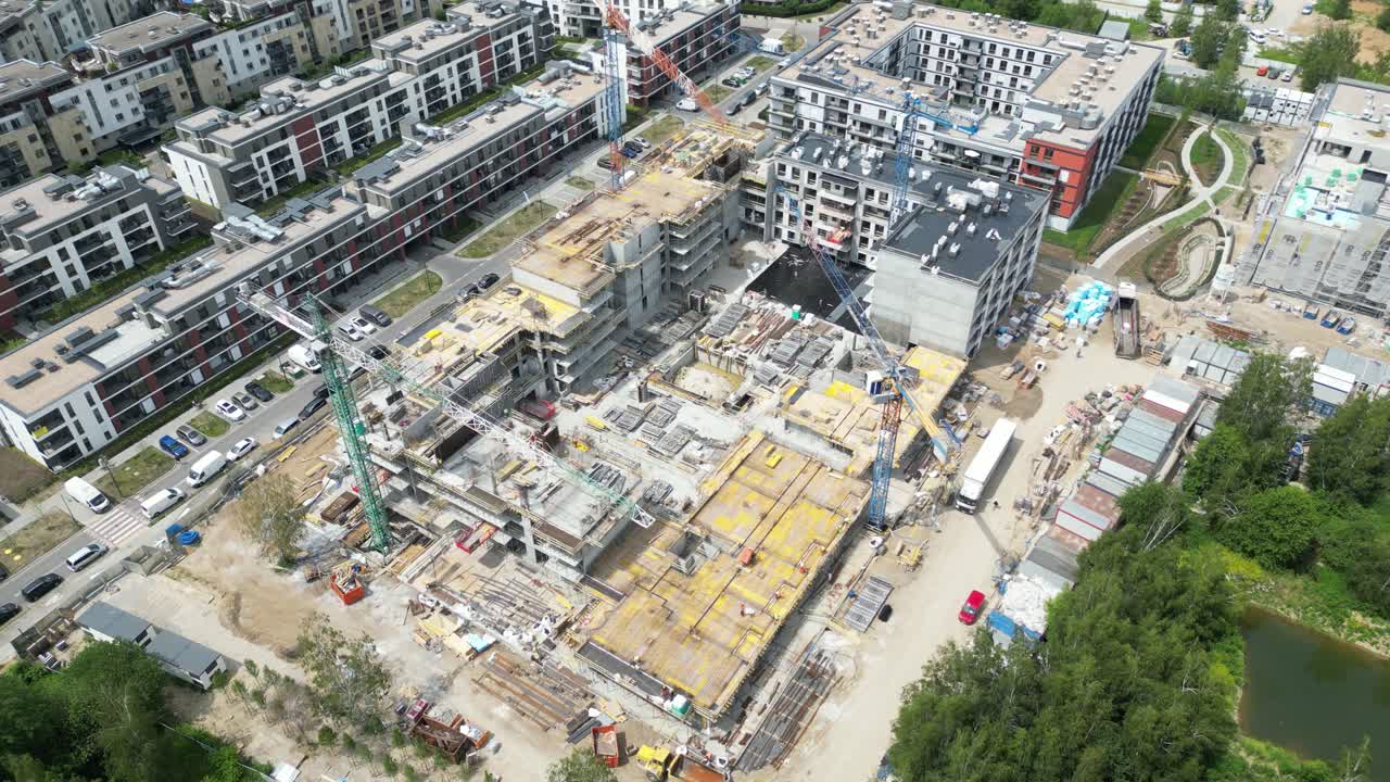 vista aérea de arriba hacia abajo en el techo de un edificio de apartamentos en construcción con una grúa de torre y muchos trabajadores colocando barras de metal