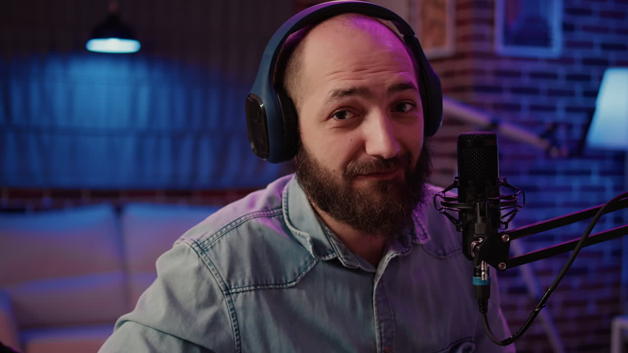 Portrait of man recording podcast talking in professional microphone sitting at desk with audio mixer