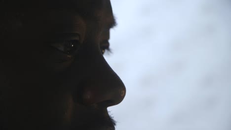 close up of black male eyes working at computer desk and listening to music