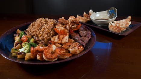 cena hibachi de surf y césped con albóndigas, filete de langosta de camarones vieiras arroz frito verduras mixtas apiladas en el plato, control deslizante 4k