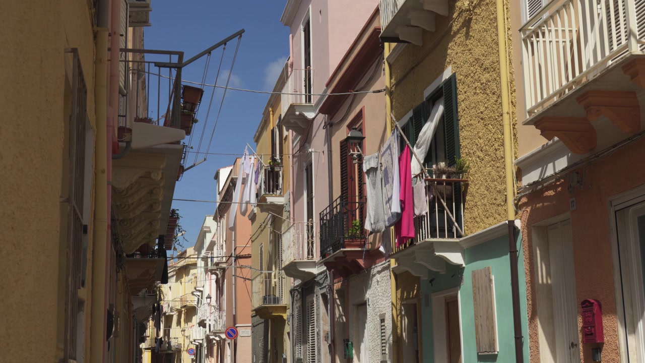 Panni stesi sugli edifici lungo una via stretta a Carloforte, in Sardegna, Italia. - Inquadratura ampia.