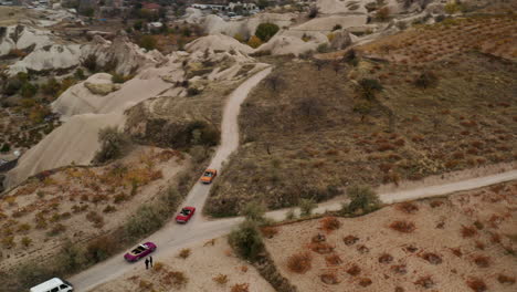 aerial view of van and vintage convertible cars driving through dirt road in cappadocia, turkey