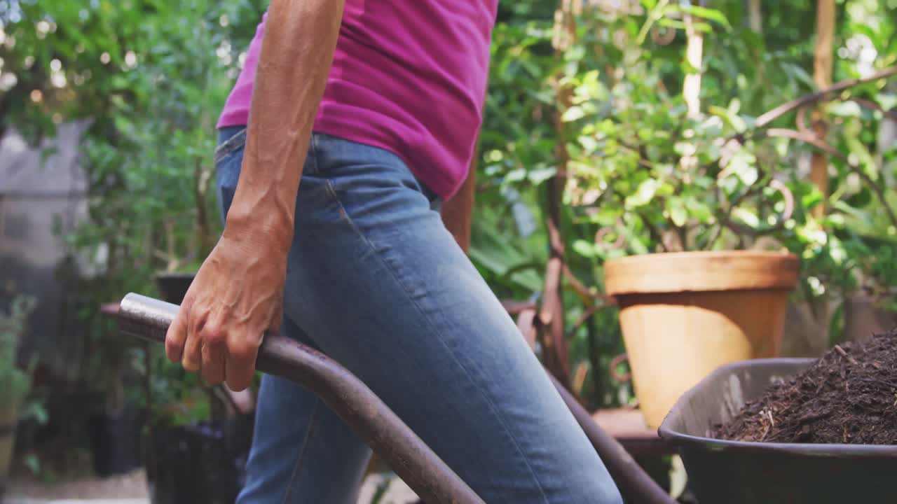 Woman pushing a wheelbarrow and gardening in a botanical garden