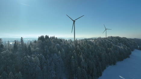 large wind turbines rotating on the top of a swiss mountain on a bright cold winter day