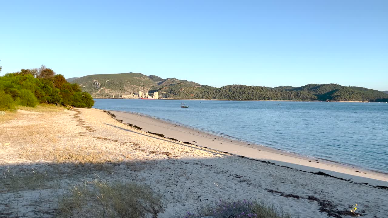 Boat anchored, floating in a calm and tranquil ocean with Set&uacute;bal in the background