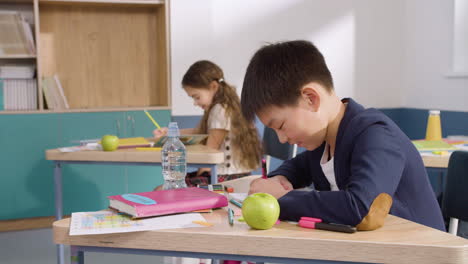 Vista-Lateral-Del-Estudiante-Y-La-Estudiante-Sentada-En-El-Escritorio-En-El-Aula-De-Inglés