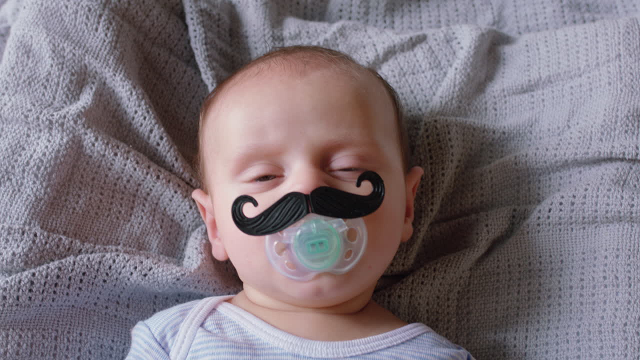 retrato de um bebê bonito com bigode chupando um boneco