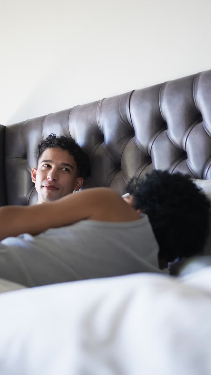Uomo che stabilisce un contatto visivo e sorride mentre il partner è sdraiato accanto a una testiera imbottita, con una luce soffusa per il benessere.