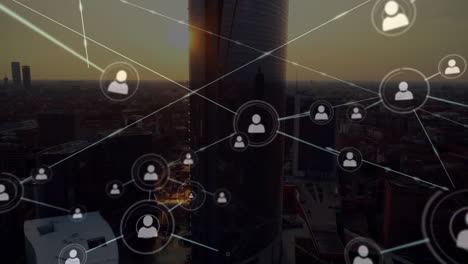 animation of network of profile icons over aerial view of cityscape against sunset sky