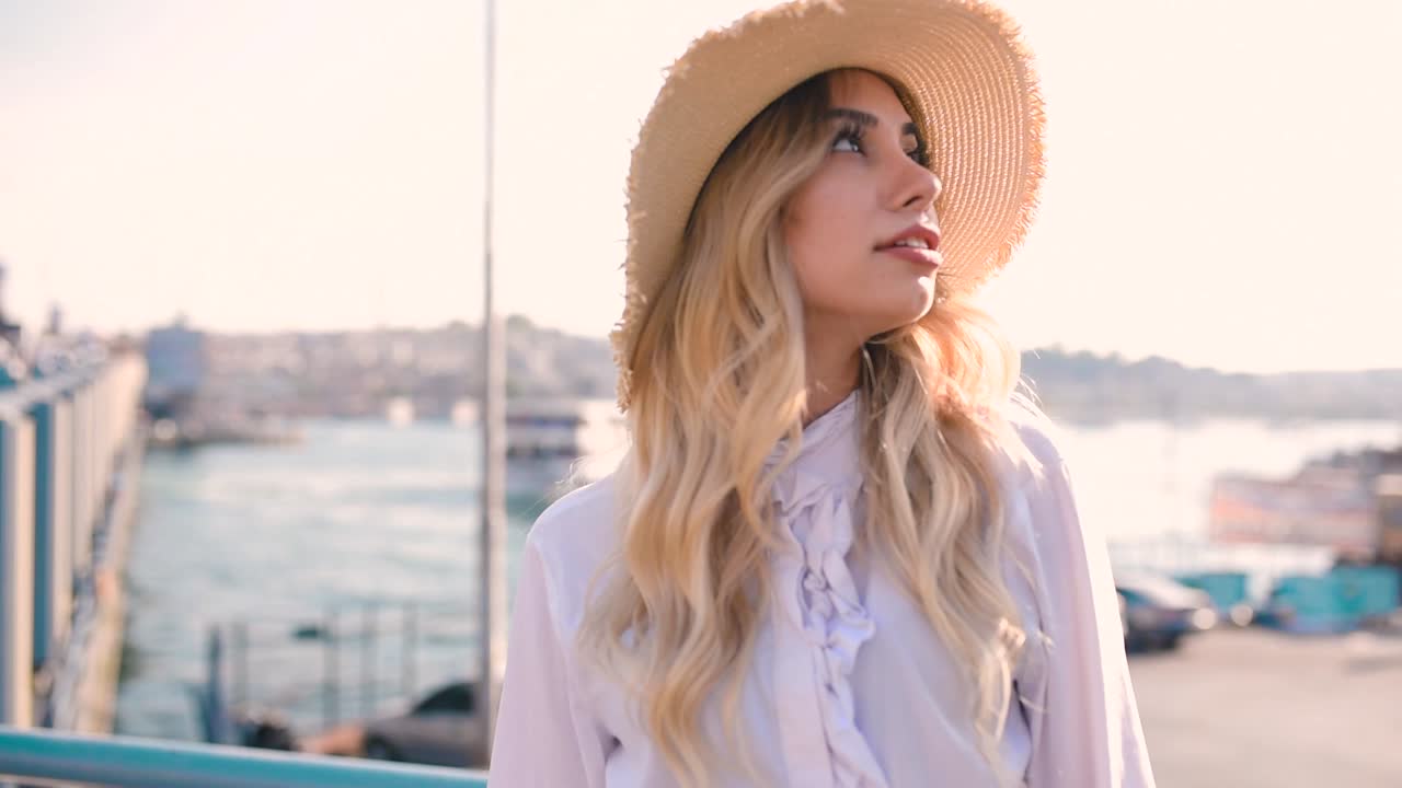 Beautiful girl poses near bosphorus with view of Galata bridge and Istanbul