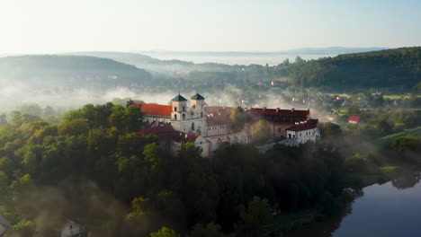 Vista-Aérea-De-Drones-De-La-Abadía-Benedictina-Sobre-El-Río-Vistula-En-Tyniec-En-La-Niebla-De-La-Mañana,-Cracovia,-Polonia