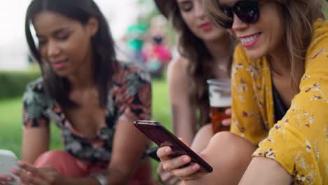 Mujer-Sonriente-Sentada-En-El-Césped-Y-Usando-Teléfono-Móvil