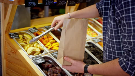 person buying dried fruit at a market